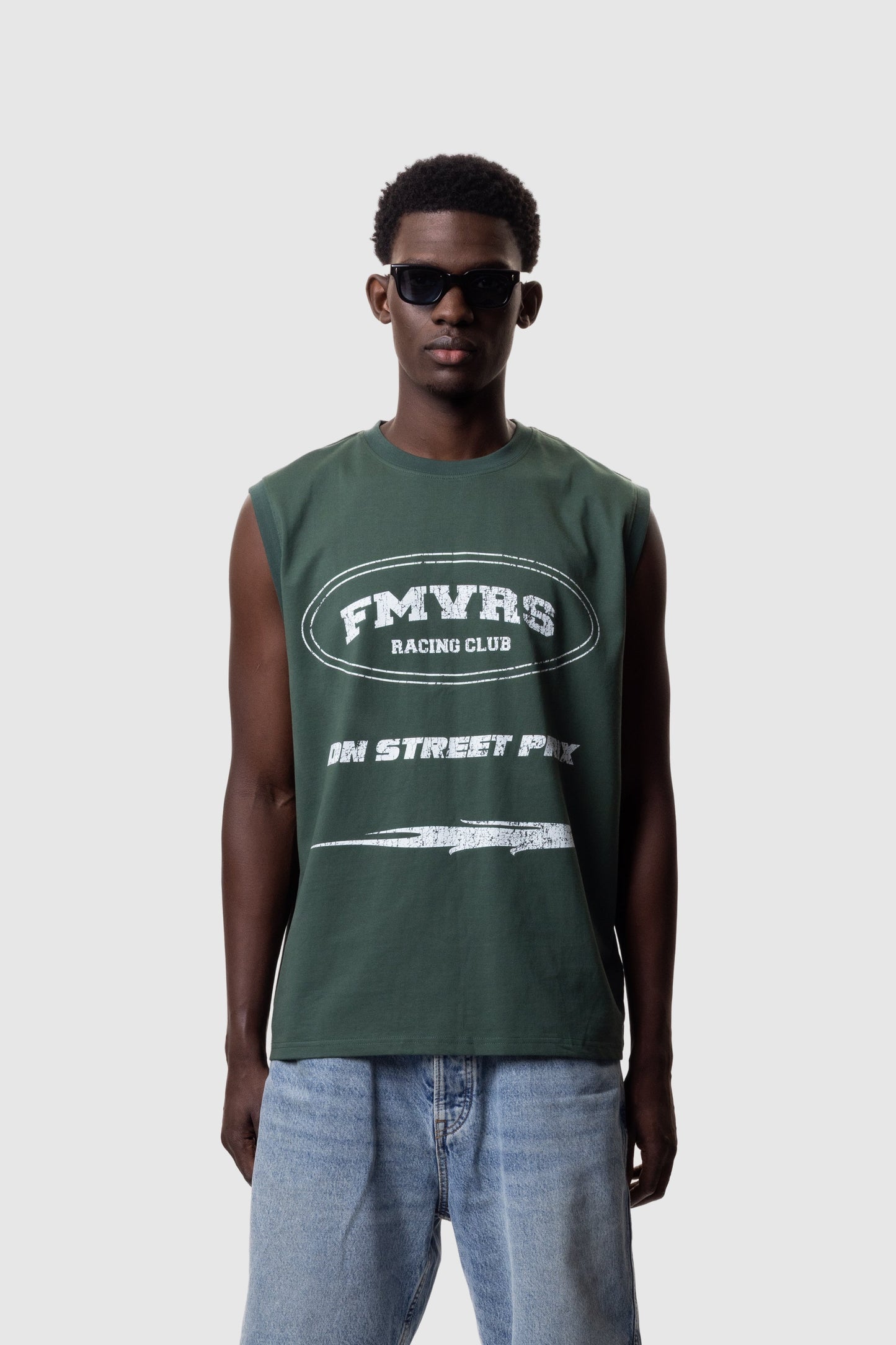 Male model wearing pine green relaxed fit sleeveless tank top with white FMVRS logo