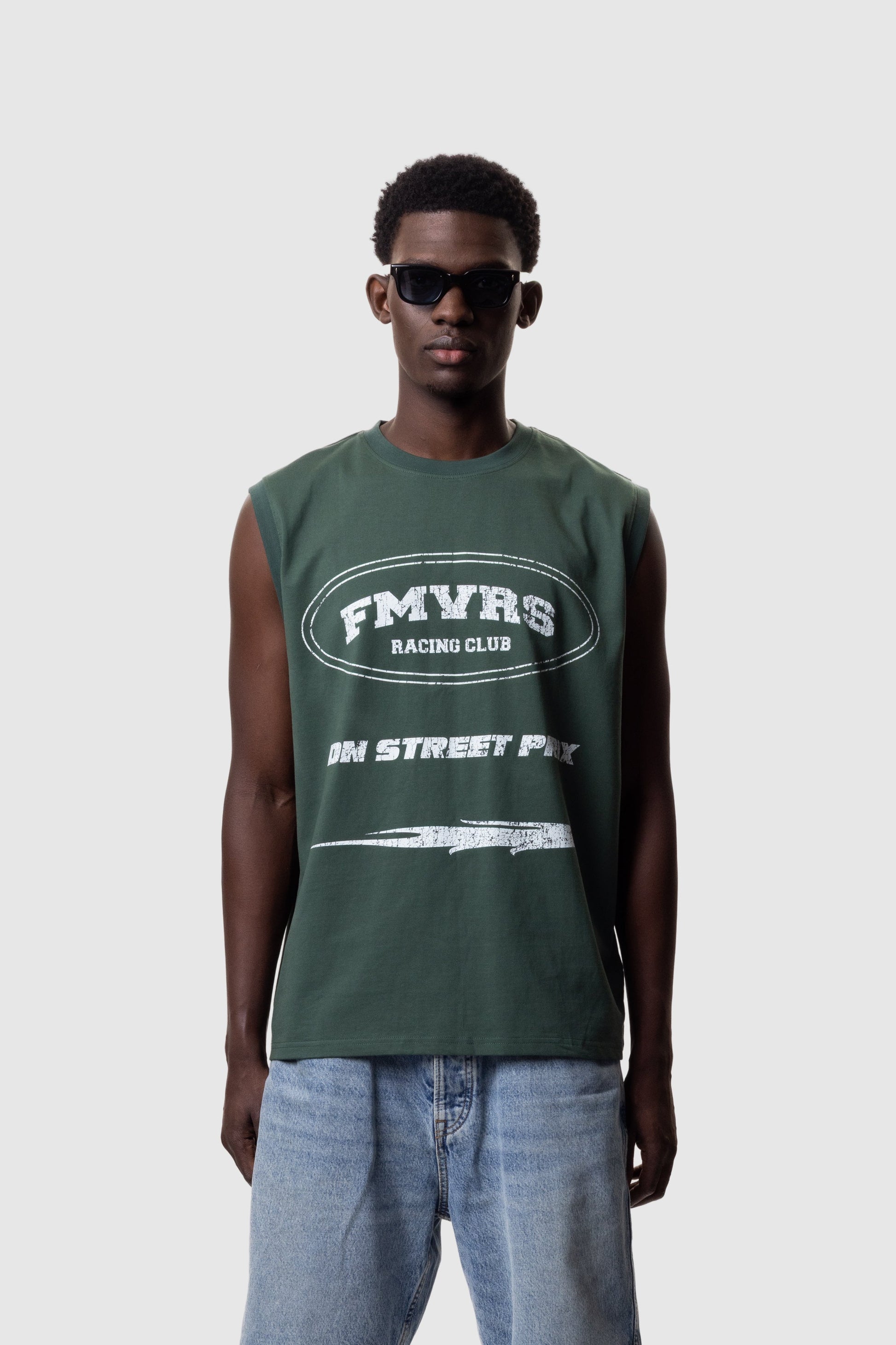 Male model wearing pine green relaxed fit sleeveless tank top with white FMVRS logo
