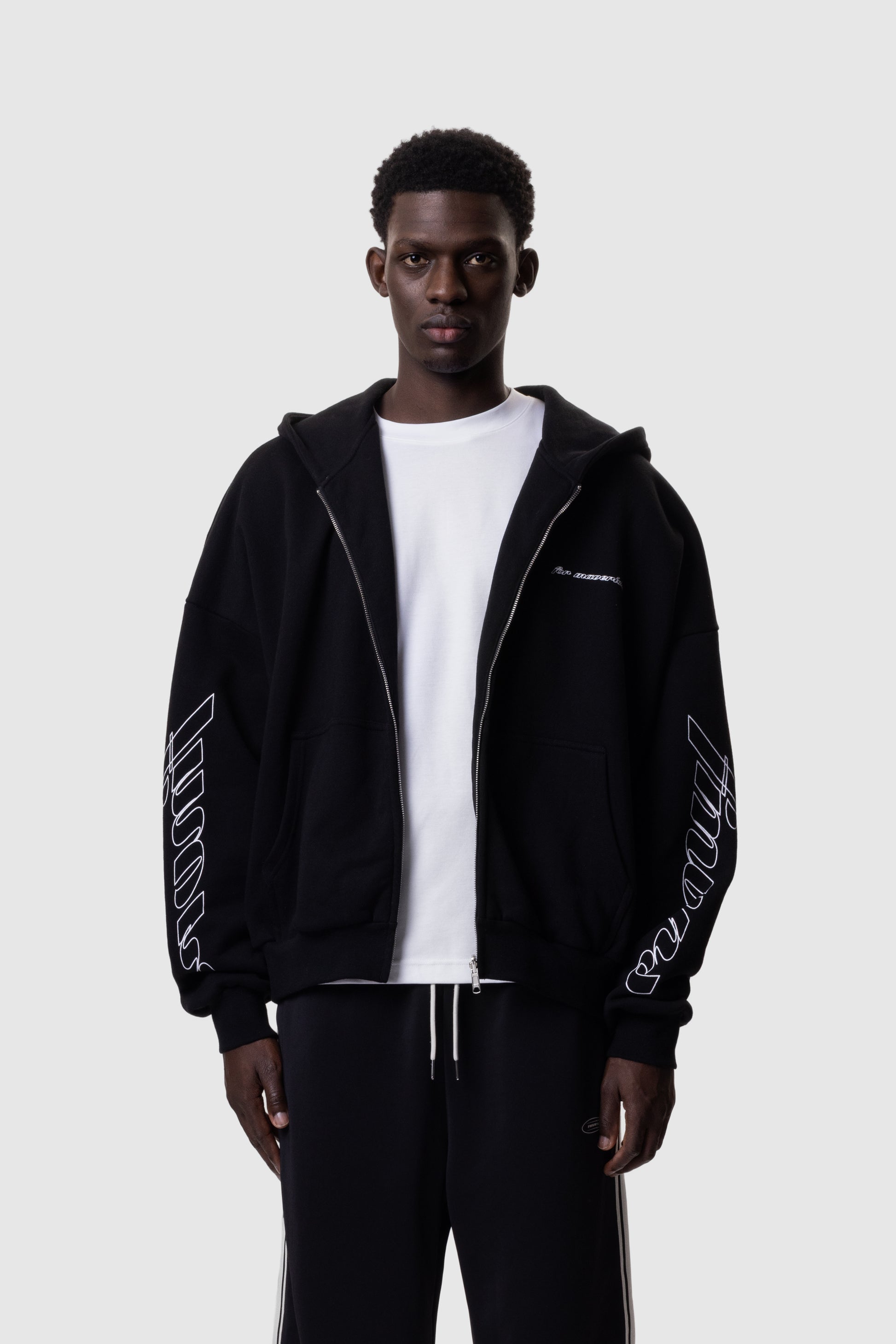 Person wearing a black hoodie with white text on sleeves against a white background