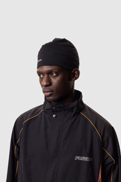 Man wearing a black jacket and beanie with 'FMVRS' branding on a light gray background