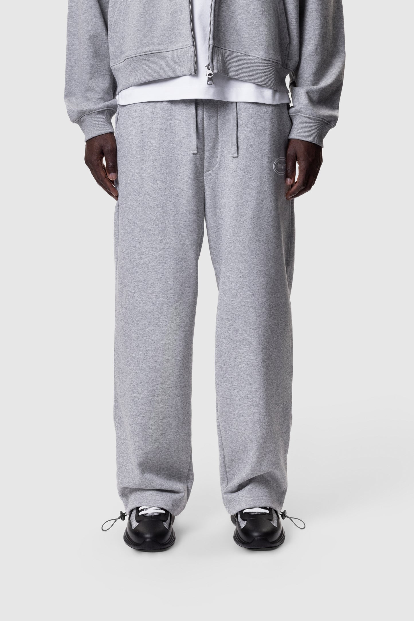 Person wearing a grey tracksuit on a white background
