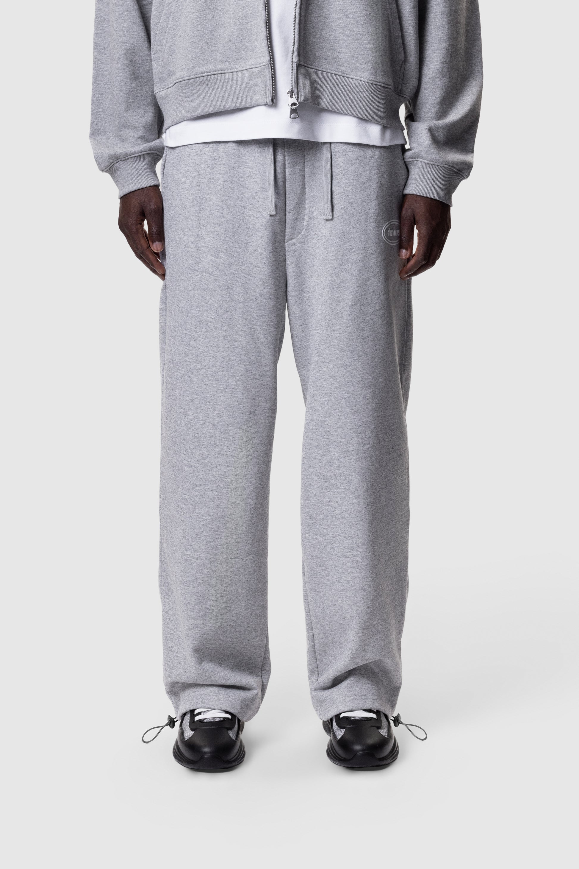Person wearing a grey tracksuit on a white background